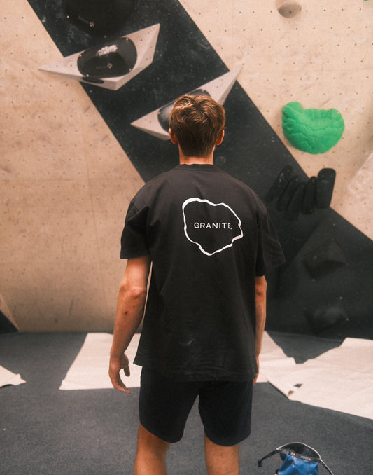 Model wearing black GRANITE. ESSENTIAL tee with white GRANITE. logo on the chest and in the back